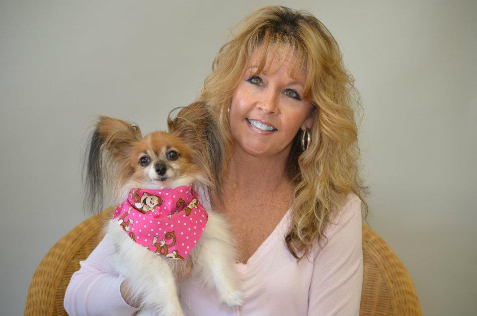 Woman holding a cute puppy that is wearing a pink bandana